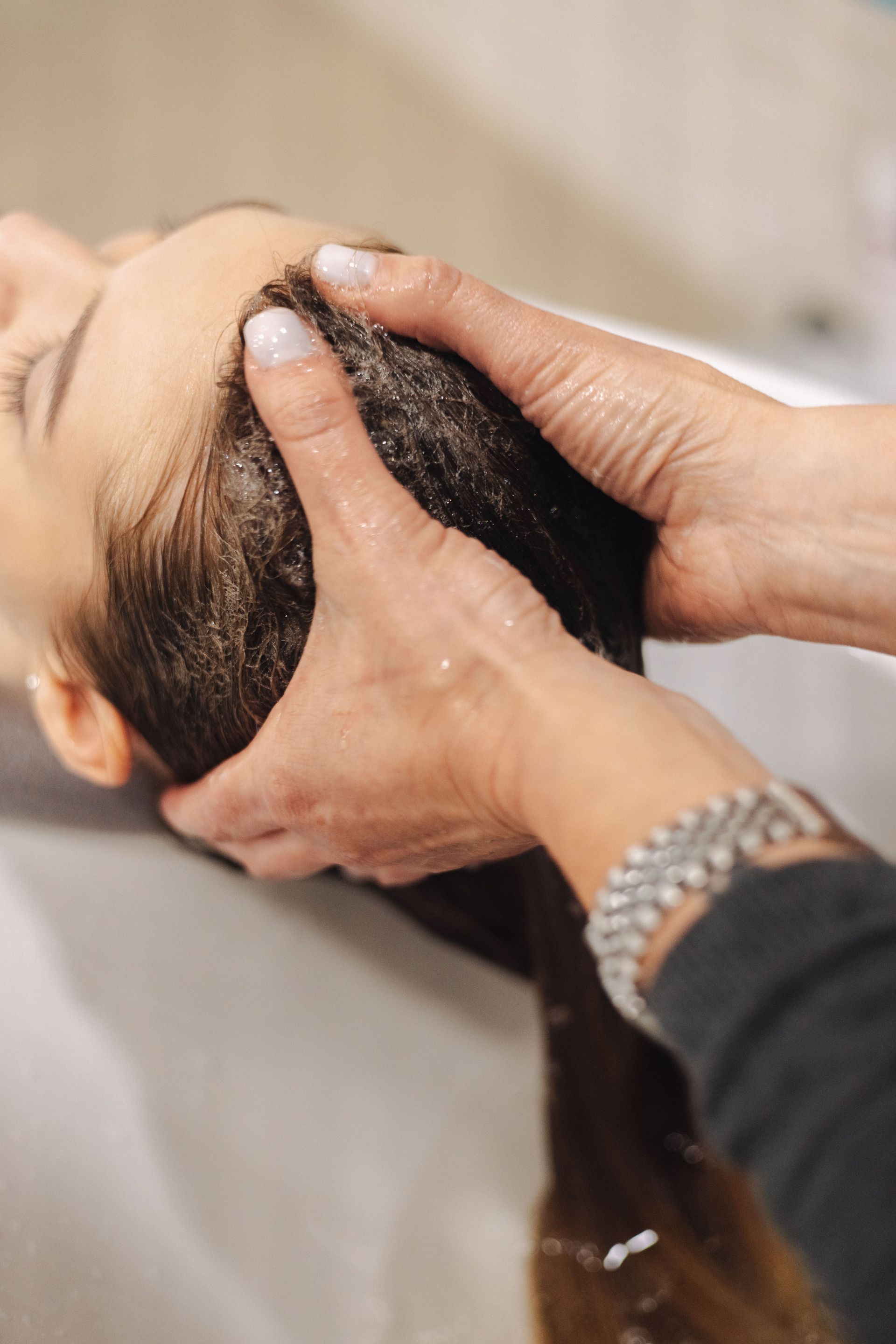 Close-up of a woman receiving a soothing head massage and hair wash at a spa.